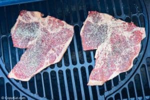 seasoned steaks on a smoker rack