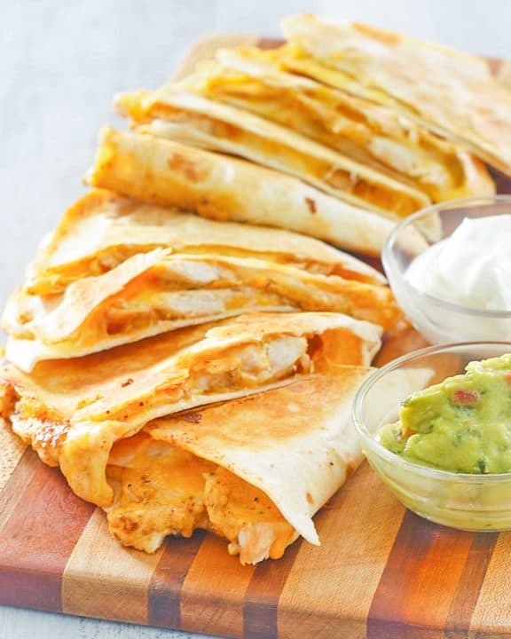 homemade Taco Bell chicken quesadilla, sour cream, and guacamole on a board