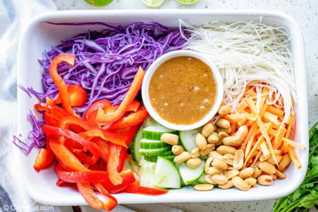 Thai noodle salad ingredients and dressing in a rectangular dish