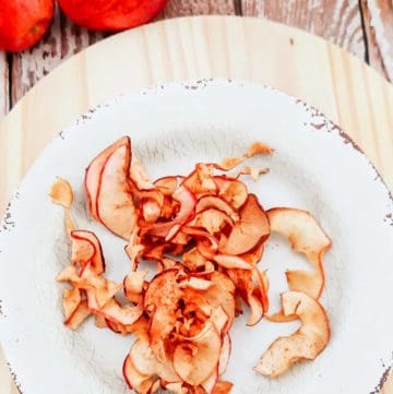 overhead view of air fryer apple chips on a plate and two apples