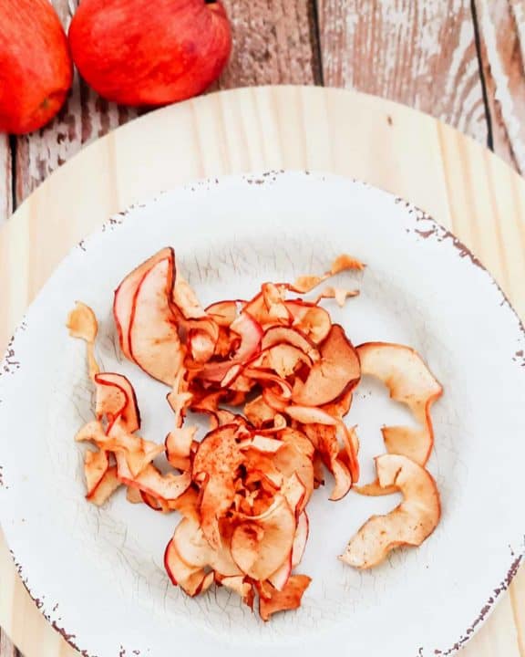 overhead view of air fryer apple chips on a plate and two apples
