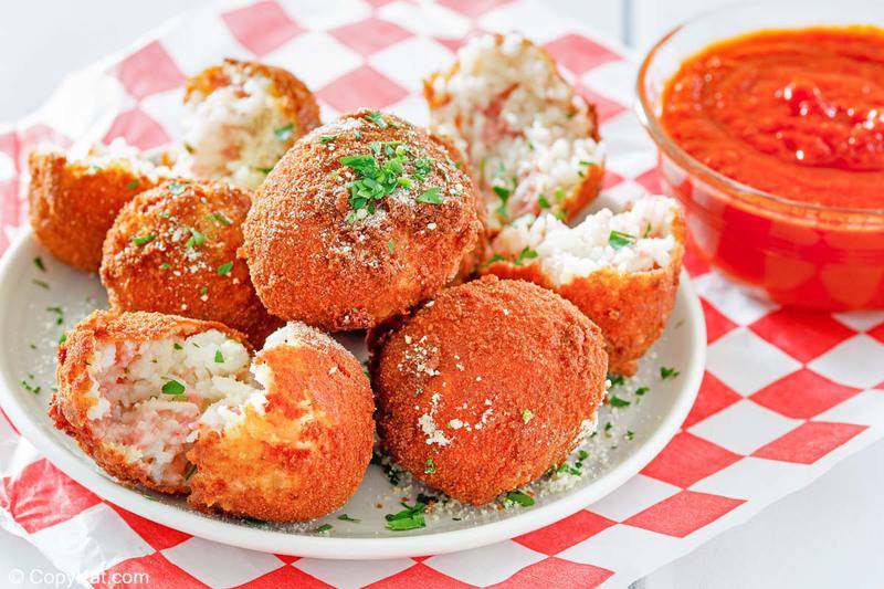 a plate of arancini Italian rice balls and a bowl of marinara sauce