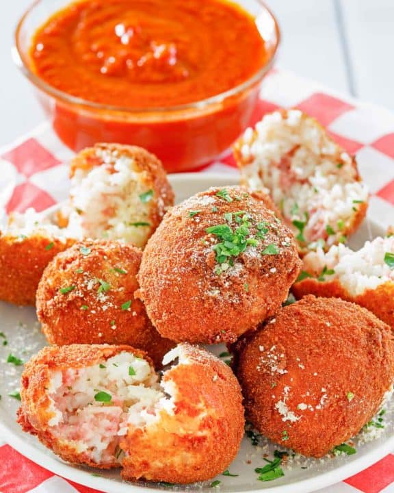 Arancini Italian Rice Balls on a plate and a bowl of marinara sauce