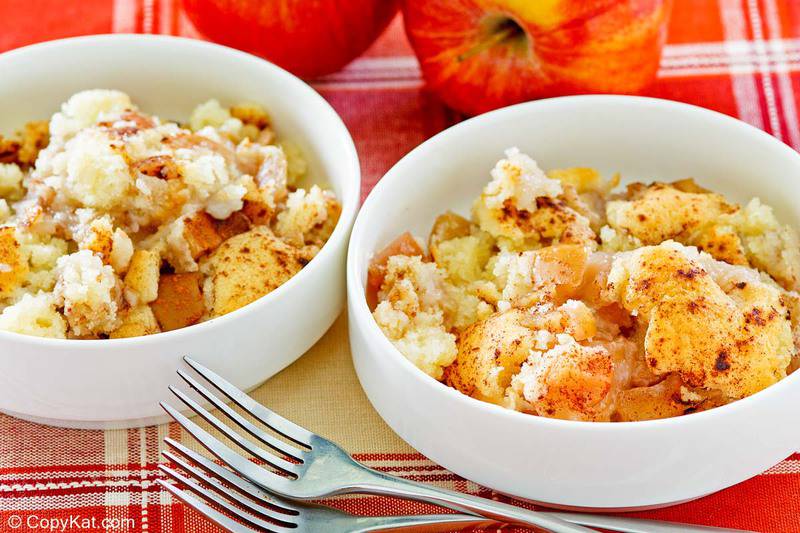 two bowls of Bisquick apple cobbler, two forks, and two apples