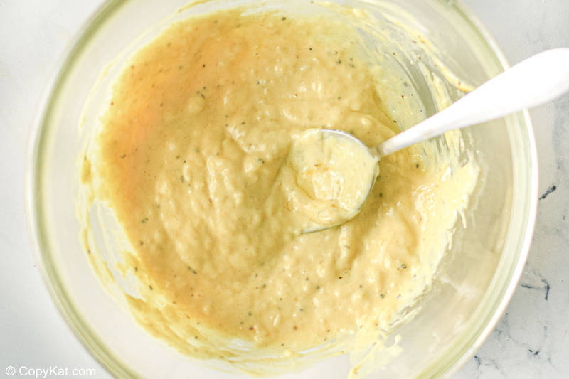 Caesar salad dressing and a spoon in a mixing bowl