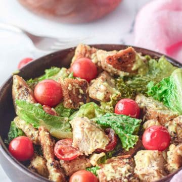 chicken Caesar salad and cherry tomatoes in wood bowls