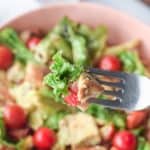 a bite of chicken Caesar salad on a fork over the salad