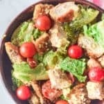 overhead view of chicken Caesar salad in a wood bowl