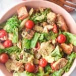 overhead view of chicken Caesar salad in a bowl and a wooden salad fork
