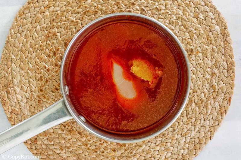 chicken and enchilada sauce in a pan