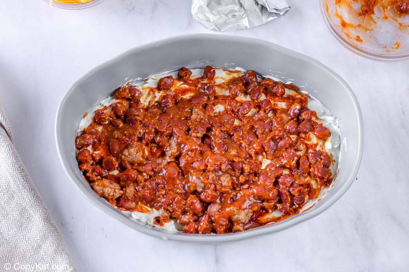chili spread on top of cream cheese in a baking dish