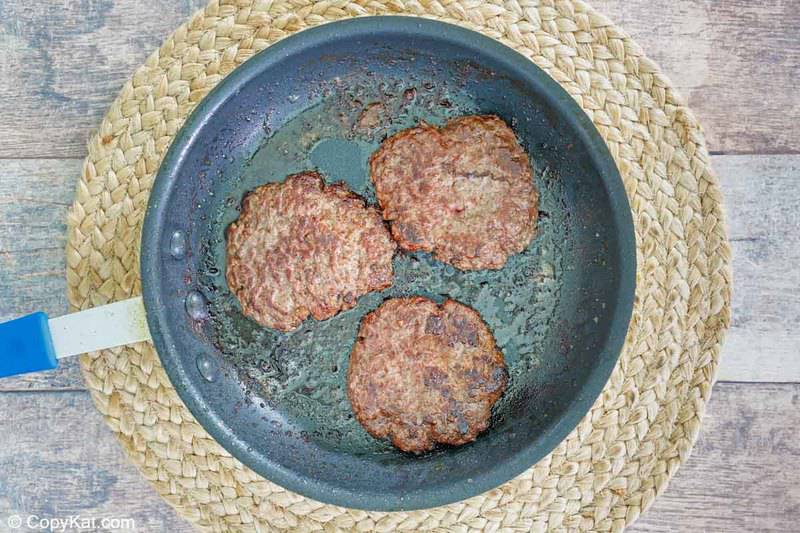 three cooked hamburger patties in a skillet