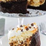 cookie dough cheesecake slice on a plate and the cheesecake on a stand