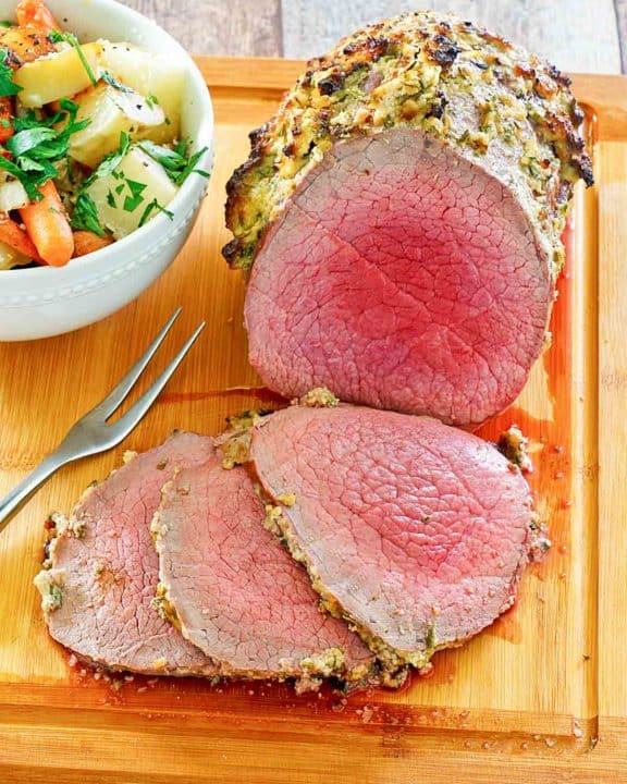 eye of round roast and a bowl of vegetables on a cutting board