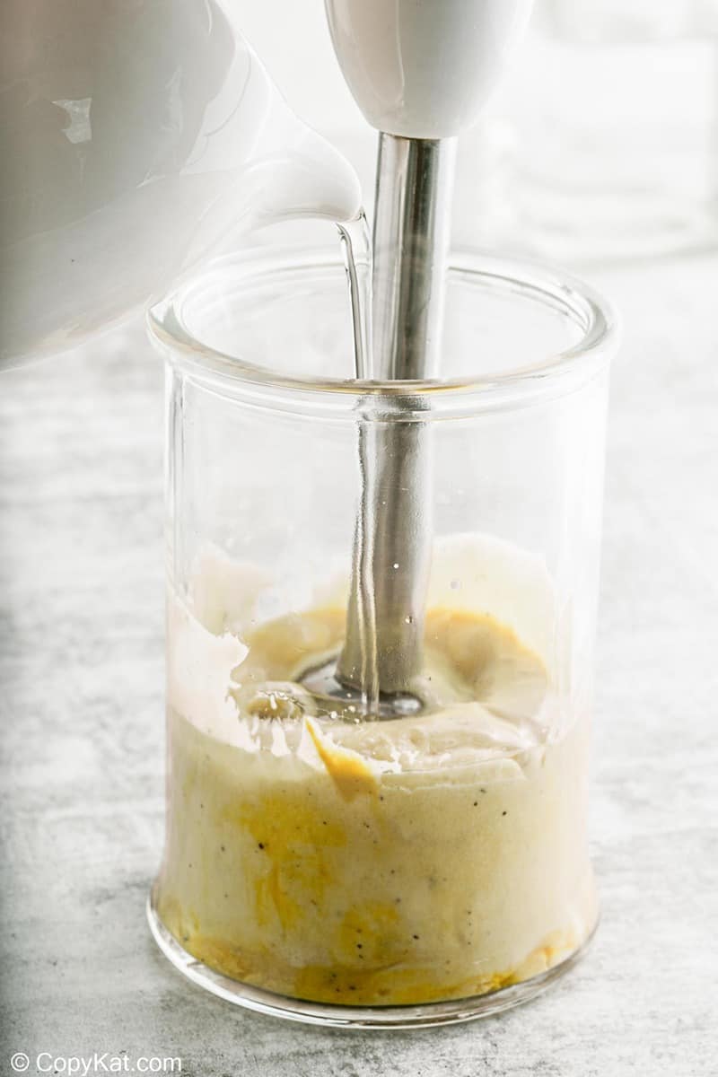 adding oil into garlic aioli mixture