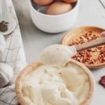 garlic aioli in a bowl, eggs, and red pepper flakes