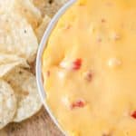 a bowl of rotel dip next to tortilla chips