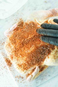 rubbing seasoning on a whole chicken
