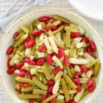 three bean salad, fork, plates, and wooden spoon