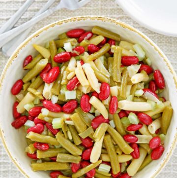 three bean salad, fork, plates, and wooden spoon