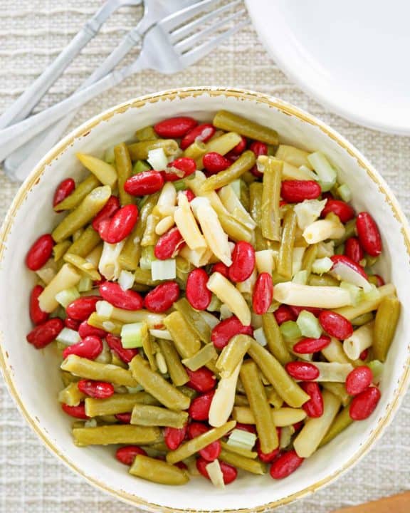 three bean salad, fork, plates, and wooden spoon