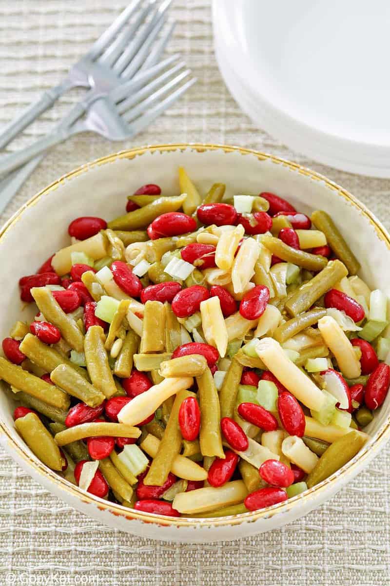 three bean salad in a bowl, forks, and plates
