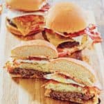 three breakfast burgers on a wood board