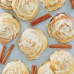 overhead view of frosted cinnamon rolls and cinnamon sticks