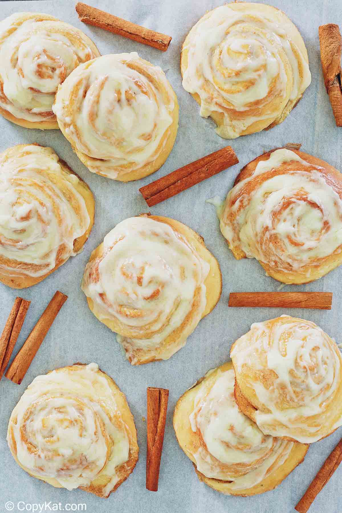 overhead view of frosted cinnamon rolls and cinnamon sticks
