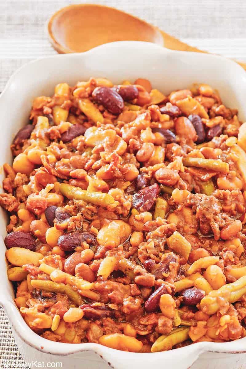 calico beans in a serving dish and a wooden spoon