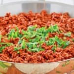 chili colorado con carne in a skillet topped with chopped cilantro