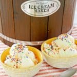 two bowls of homemade vanilla ice cream, two spoons, and ice cream maker