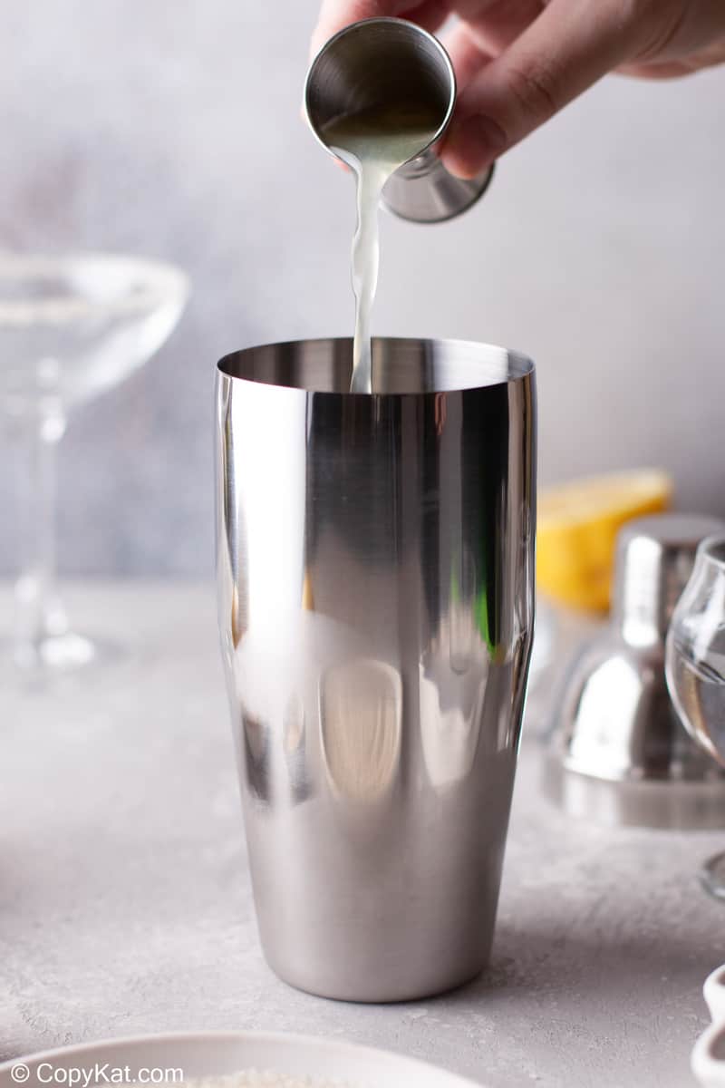 pouring lemon juice into a cocktail shaker