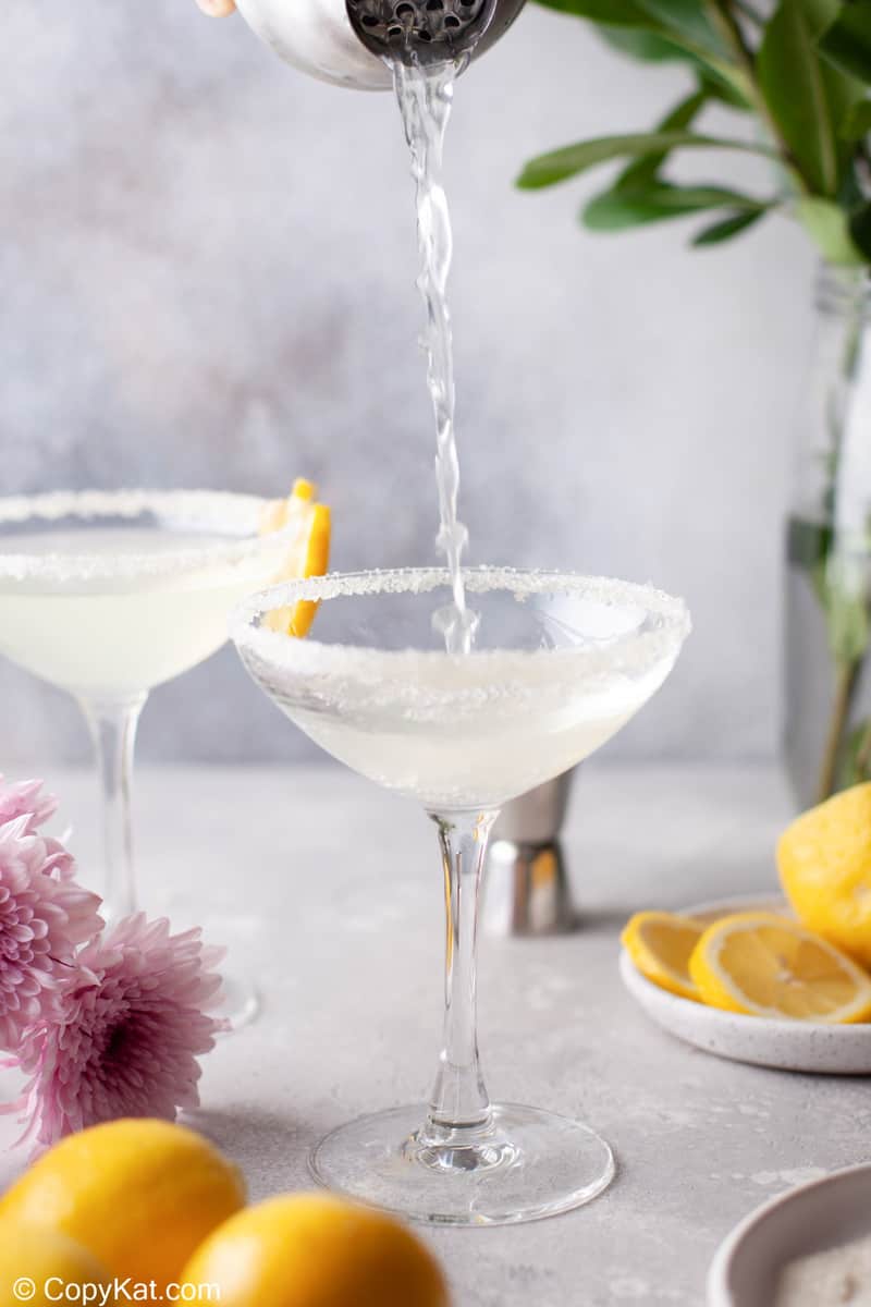 pouring a lemon drop martini into a sugar rimmed glass