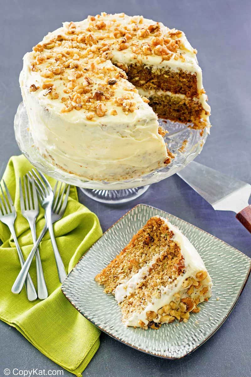 zucchini cake slice on a plate and the cake on a stand