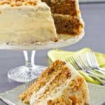 zucchini cake with cream cheese frosting on a cake stand and a slice on a plate