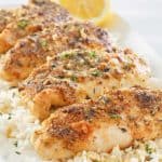 baked lemon pepper chicken over rice on a platter.