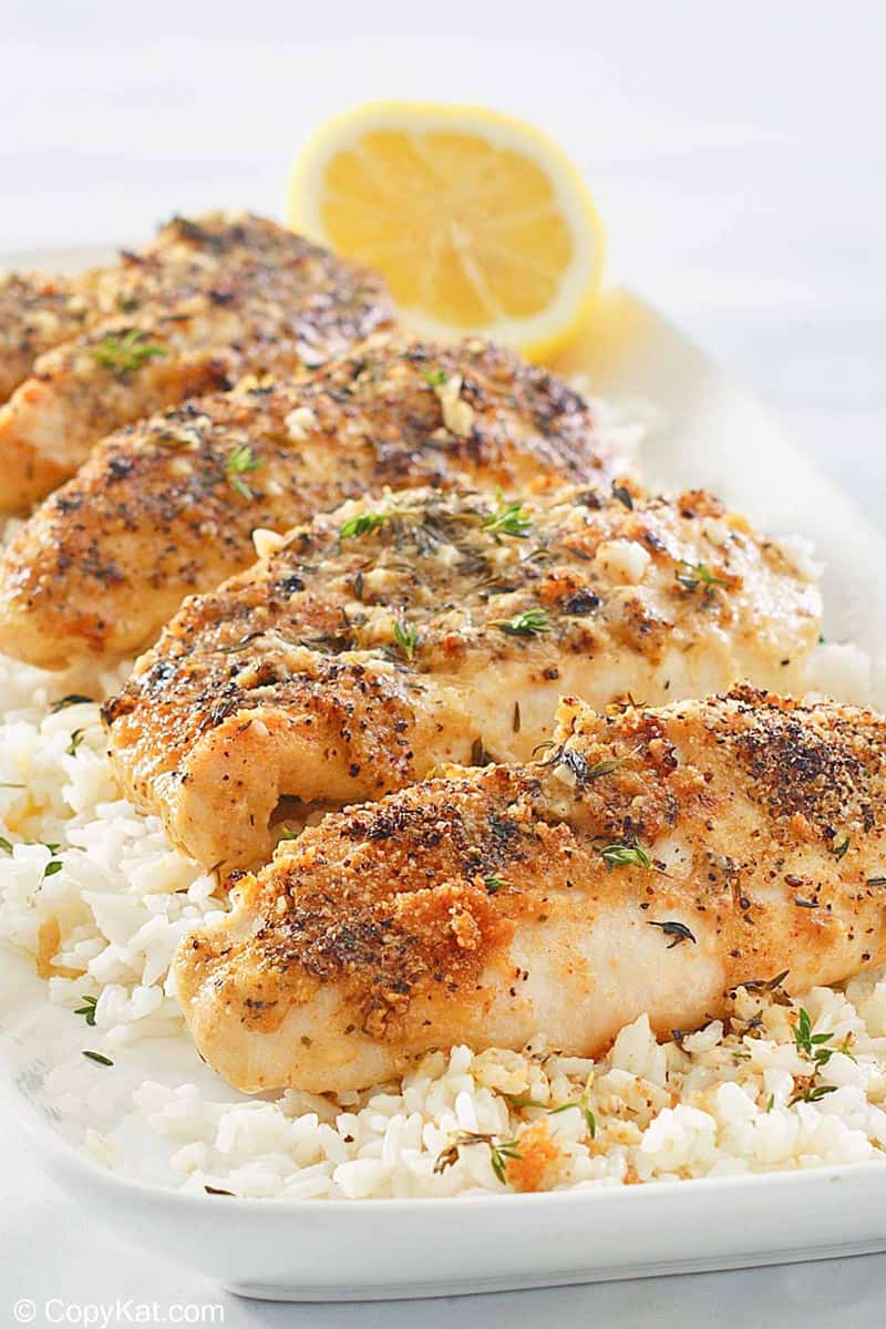 baked lemon pepper chicken over rice on a platter.