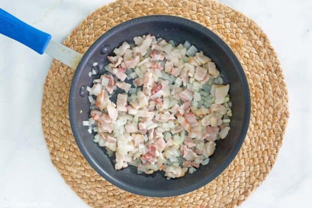 cooked onions and bacon pieces in a skillet.