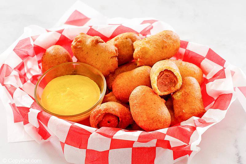 mini corn dogs and mustard in a serving basket.