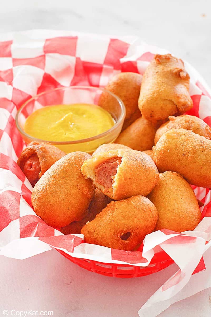 mini corn dogs and a small bowl of mustard in a basket.