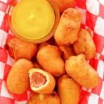 mini corn dogs and mustard on parchment paper.