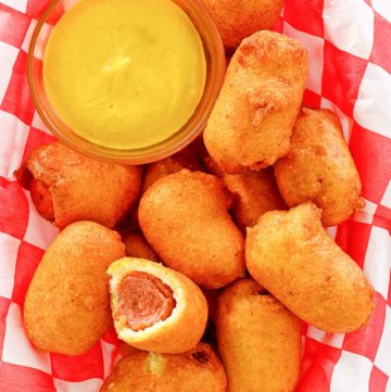 mini corn dogs and mustard on parchment paper.
