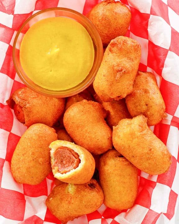 mini corn dogs and mustard on parchment paper.