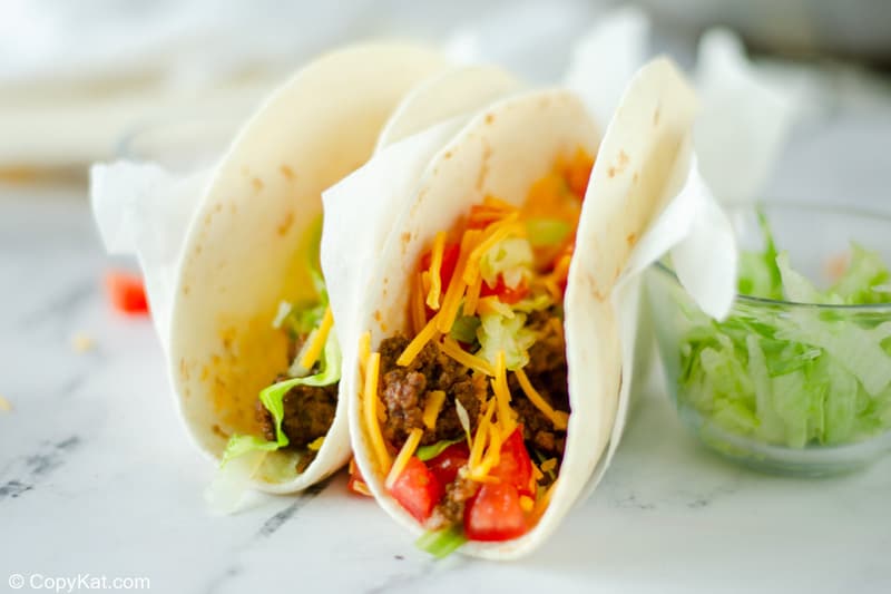 two homemade Taco Bell soft tacos and shredded lettuce in a small bowl
