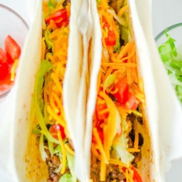 two homemade Taco Bell soft tacos with beef, lettuce, cheese, and tomatoes