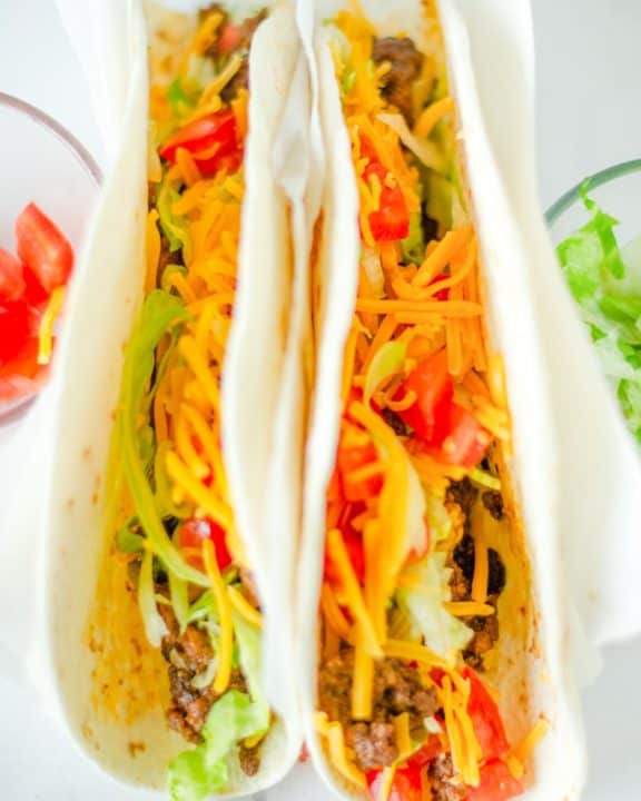 two homemade Taco Bell soft tacos with beef, lettuce, cheese, and tomatoes