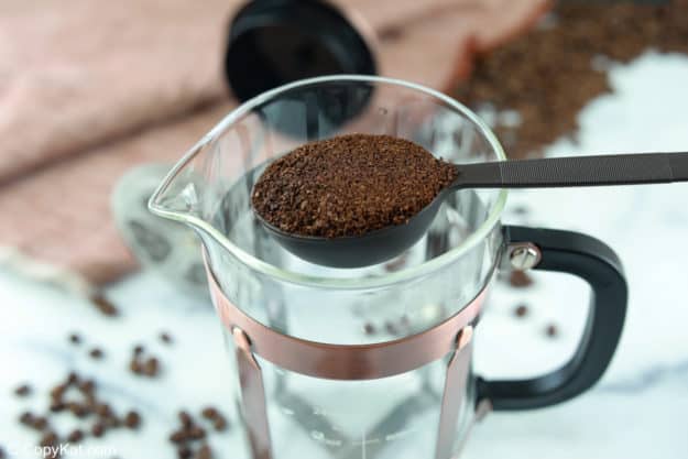 a scoop of coffee grounds over a French press.