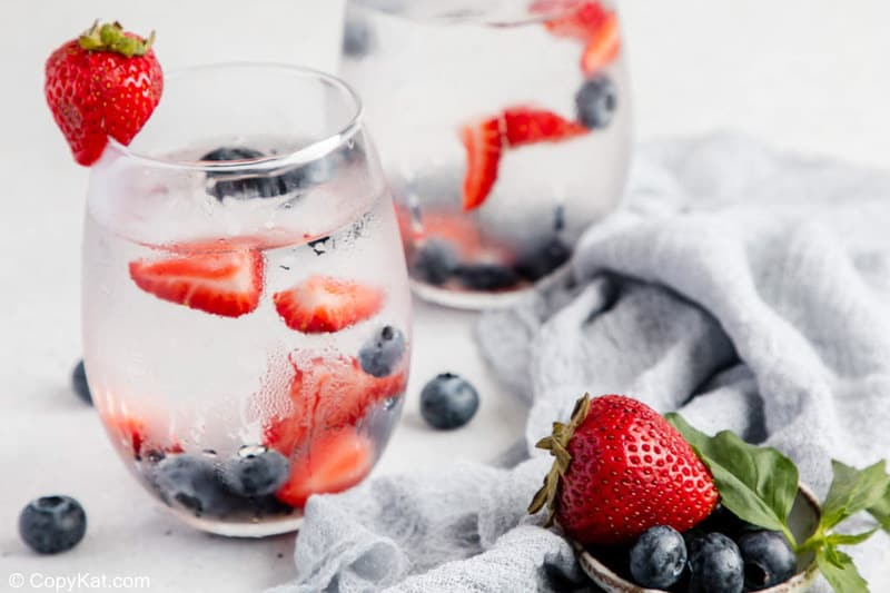 Glasses filled with berry infused water and fresh fruit.