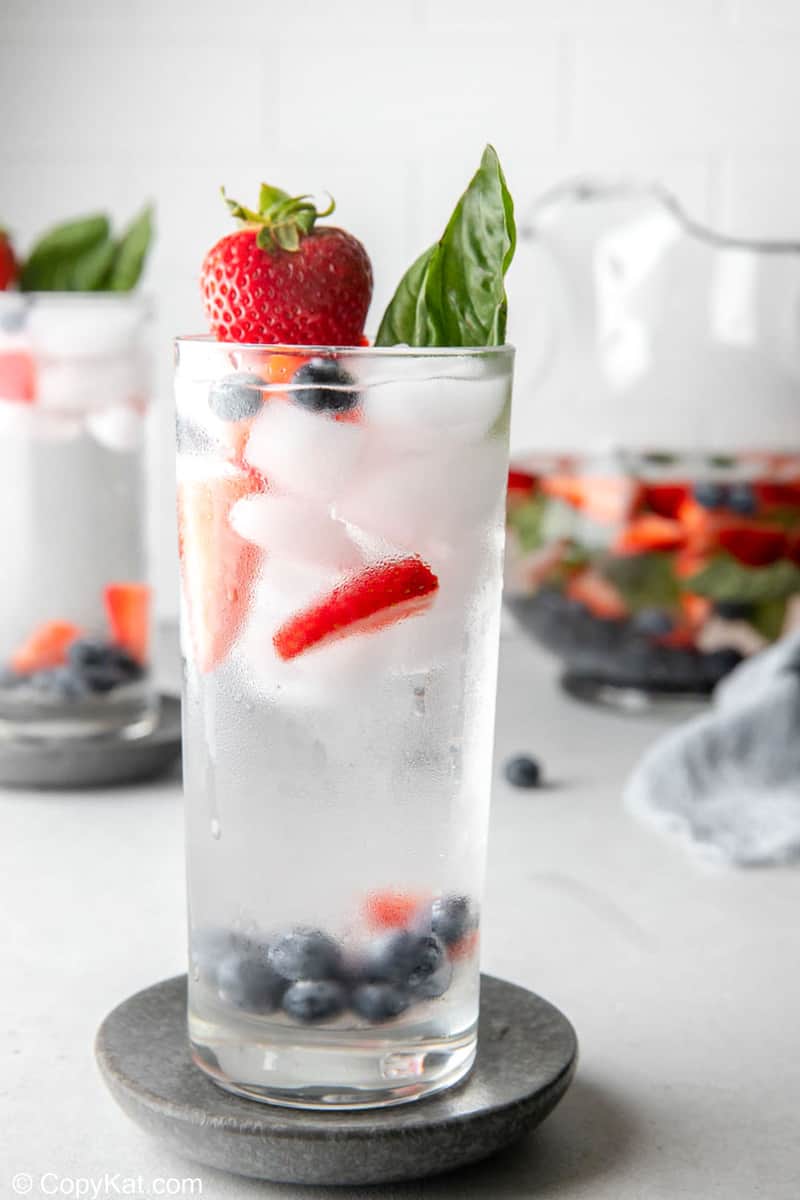 tall glass filled with fruit infused water, fresh fruit, and ice.